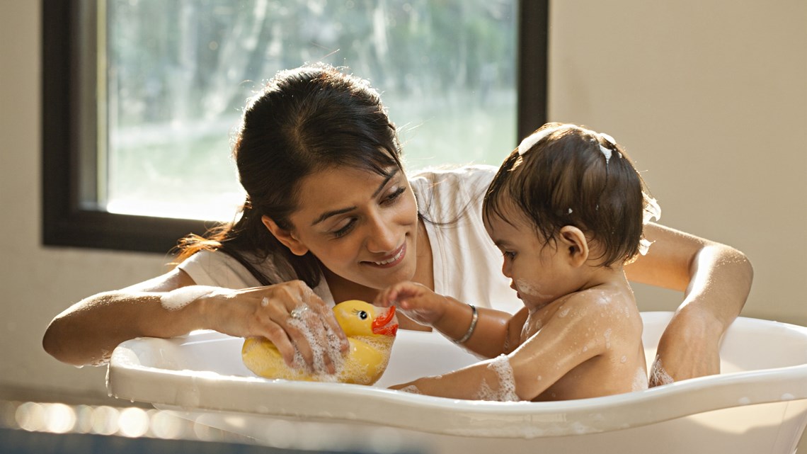 Mother bathing baby in small tub